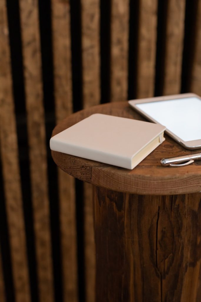 Notebook with pen and tablet on table